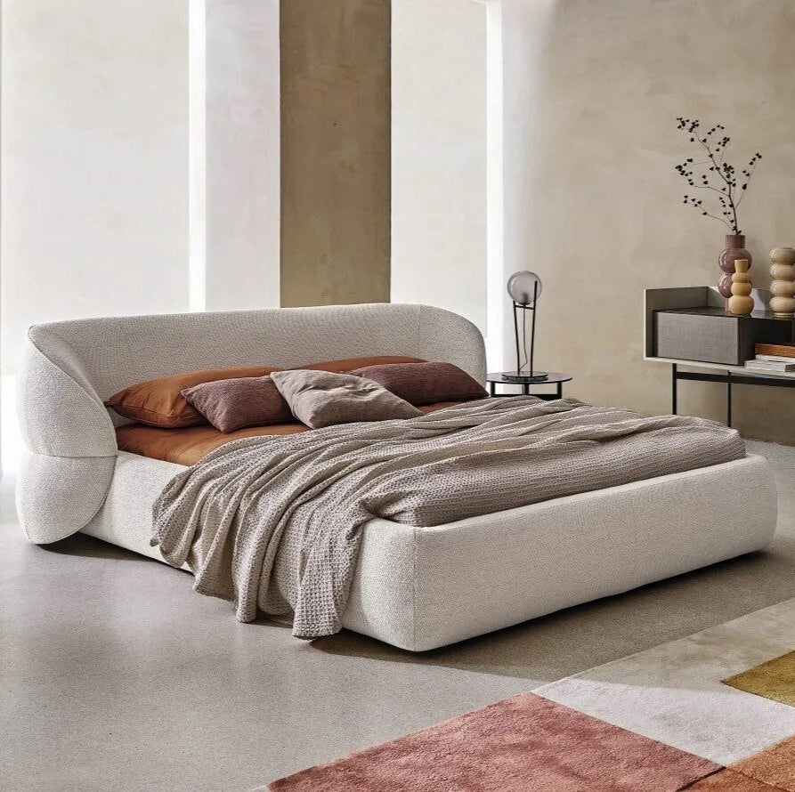 Lit design Isobel en tissu bouclé beige, chambre moderne avec mur en tadelakt et fauteuil gris.