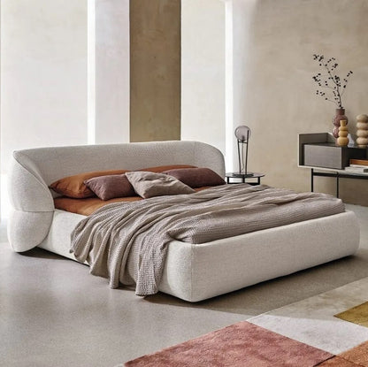 Lit design Isobel en tissu bouclé beige, chambre moderne avec mur en tadelakt et fauteuil gris.